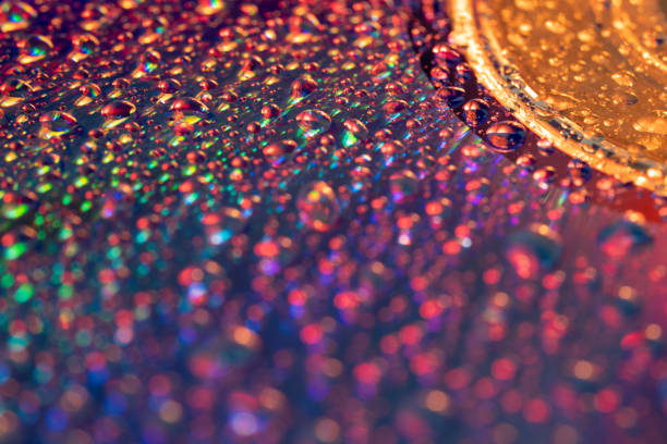 Colorful modern background of glowing light bubbles like bokeh.  Water droplets on shinny surface. Macro photography.