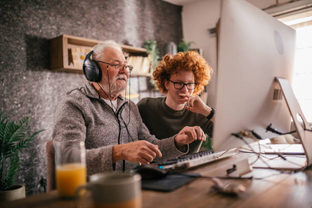 istock grandfather and grandson sitting around table at home and using computer 1453311183