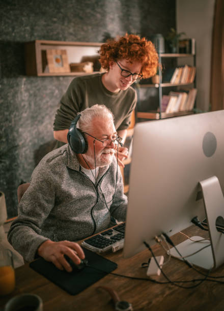 grandfather and grandson sitting around table at home and using computer