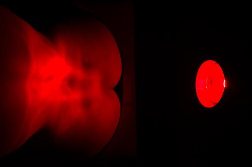 Woman with infrared Treatment back painWoman sitting on chair with a heat lamp on her lower back.