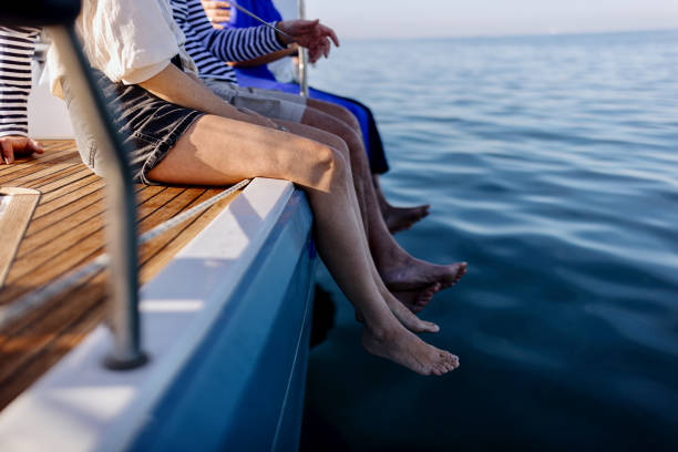 Mature adult friends sitting on sailboat's deck and enjoying the view. Luxury vacation, yacht sailing