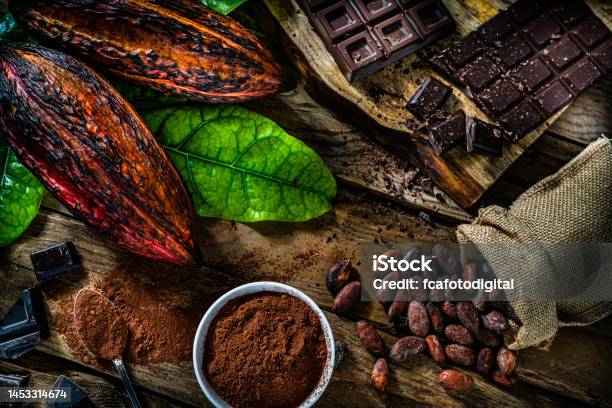 Dark Chocolate Bars Cocoa Pods And Cocoa Powder On Rustic Wooden Table Stock Photo - Download Image Now