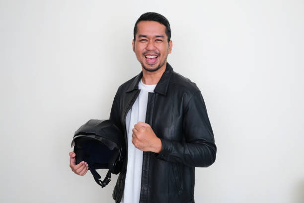 Man in leather jacket holding a motorbike helmet isolated on white background