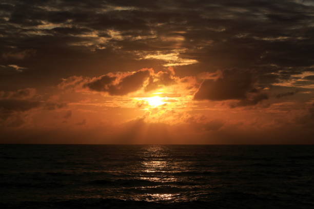 istock Morning sunrise from the sea in gray clouds 1453320029