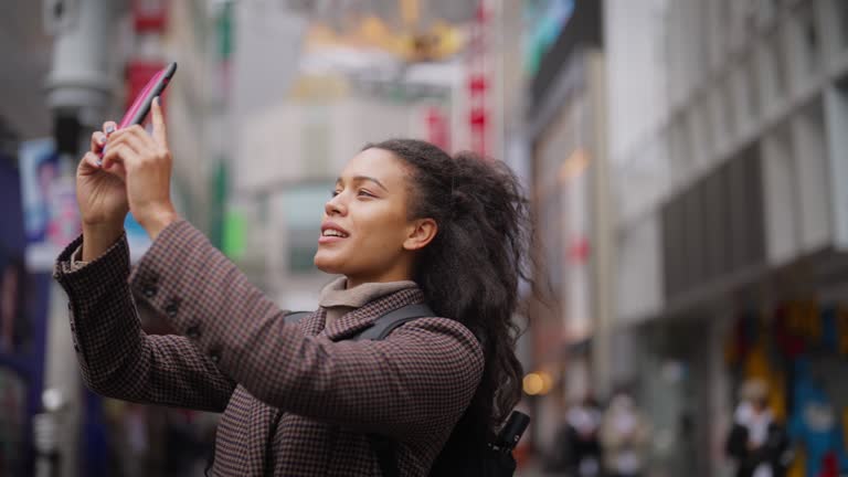 Female tourist taking photos and videos while exploring the city in Shibuya Tokyo