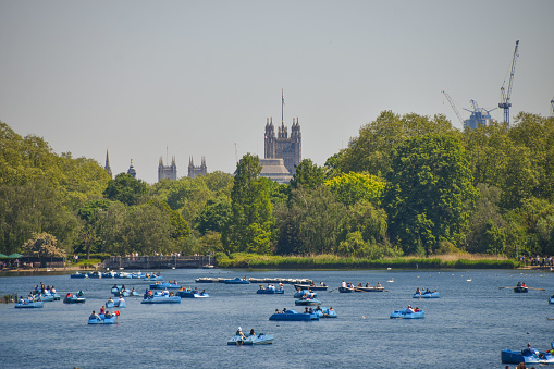 London, United Kingdom - May 31 2021. People enjoy a warm day in blue pedal boats on the Serpentine lake in Hyde Park.