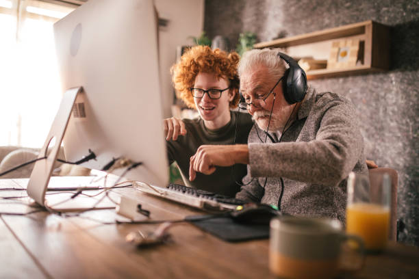 istock grandfather and grandson sitting around table at home and using computer 1453326552