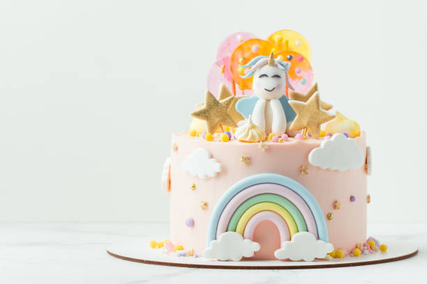 istock Unicorn cake with pink cream cheese frosting decorated with mastic rainbow, multicolored caramel candies and unicorn shaped figure on top. Birthday cake for a little girl on the white background 1453327497