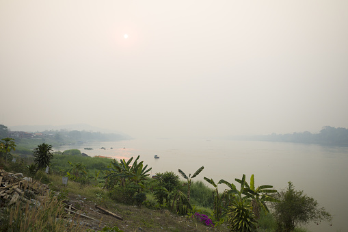 Upstream morning panorama at Mekong river in early morning and sunrise in Chiang Kham with border to Laos in morning with haze and smog in air in north of Thailand
