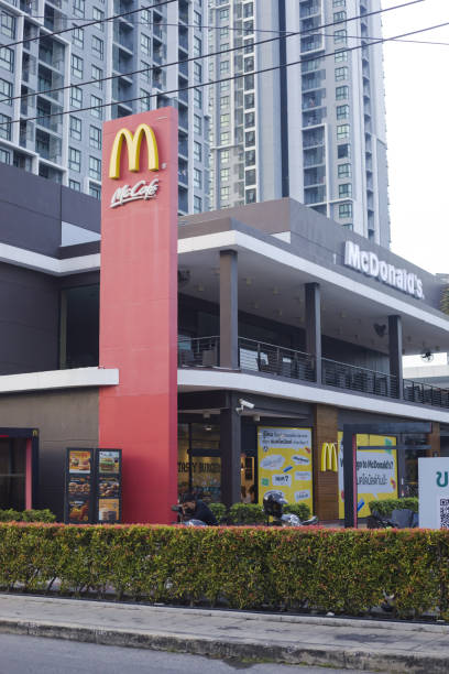 restaurante cúbico moderno do mcdonald's em frente a um enorme condomínio em bangkok - bangkok mcdonalds fast food restaurant asia - fotografias e filmes do acervo