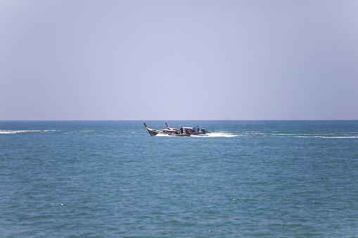 Thai longboat is overtaking another one at high speed in Andaman Sea seen from beach in Krabi in south Thailand