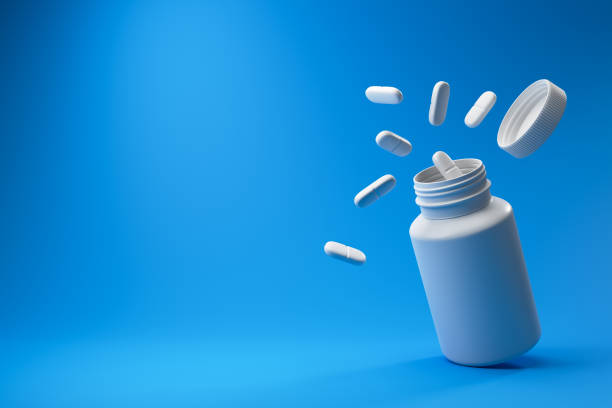 istock White pills and plastic medical container on a blue background. 1453330982