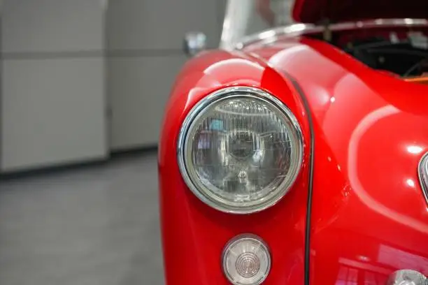 Photo of Closeup of red retro volkswagen beetle car headlight