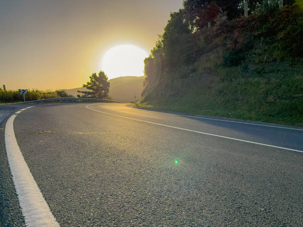 Mountain road at sunrise with sun in the background