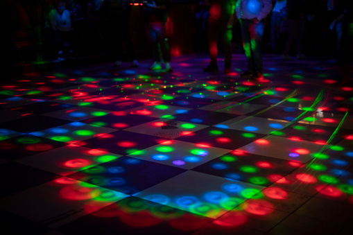 Disco on dance floor. Flower spots on floor. Color music indoors. Coloured spotlights.