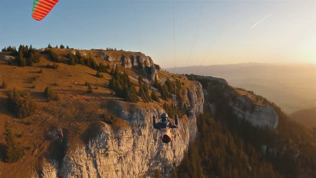 Freedom of paragliding fly above forest and rocks in autumn mountains at golden sunrise, Adrenaline adventure relaxation flight