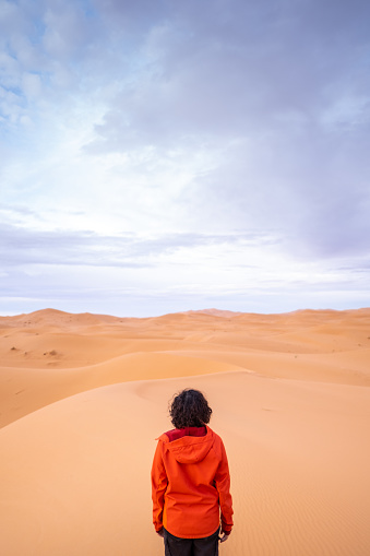 Woman observes the immensity of the desert dunes in solitude. Loneliness influences physical and mental wellness.