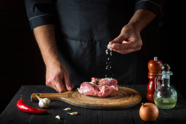 istock The cook sprinkles the meat with salt. Preparing meat before baking. Working environment in restaurant kitchen 1453337171