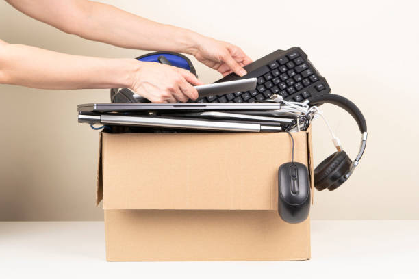 istock Female hands put tablet computer and keyboard in box full old used computers and gadget devices for recycling. Planned obsolescence, e-waste, donation, electronic waste for reuse and recycle concept 1453338259