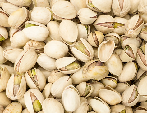 Background of organic pistachios. Natural pure pistachios nuts texture background. Scattered pistachios grains pattern