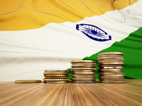 Rising stack of coins with Indian flag in the background. Economy, finance, interest rates concept.