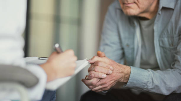 doctor talks with patient and takes notes - visit hospital patient senior adult imagens e fotografias de stock