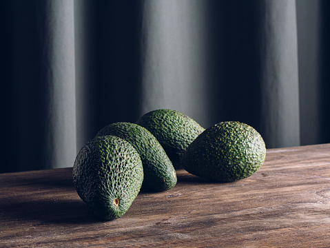 4 fresh avocados on a wooden table, isolated on gray background