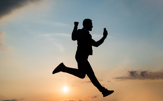 Profile view of aged 30-39 years old with black hair caucasian young male athlete running in front of black background wearing leggings who is happy