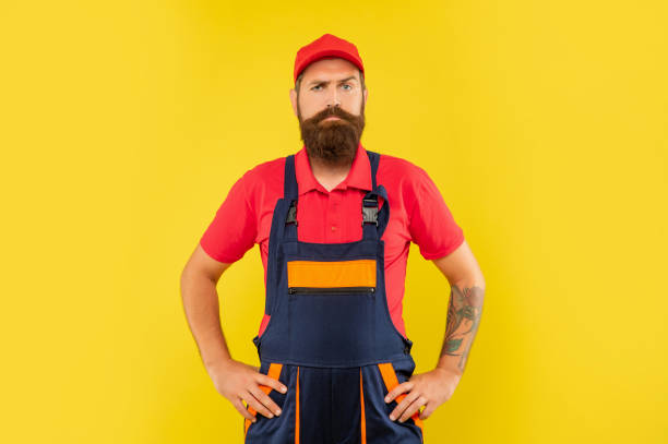 istock serious bearded man plumber in work clothes on yellow background 1453346469
