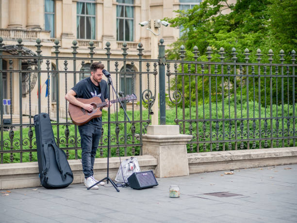 jeune artiste de rue avec une guitare acoustique jouant dans le centre de bucarest (rue de la victoire - calea victoriei). - romania men artist portrait photos et images de collection