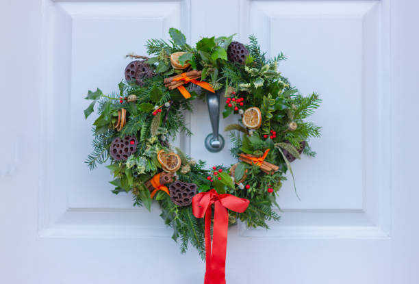 istock Christmas wreath with red bow on white door, close-up 1453348150