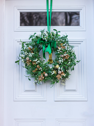 Christmas wreath with green ribbon on a white wooden door, close up