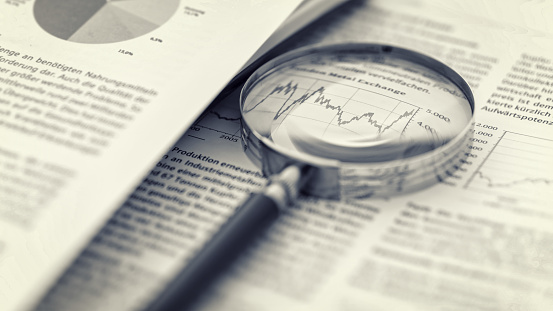 Magnifying glass, calculator and charts on paper symbolizing business and financial market. Sepia toned image. studio shot in raw format taken with prime lens for best quality
