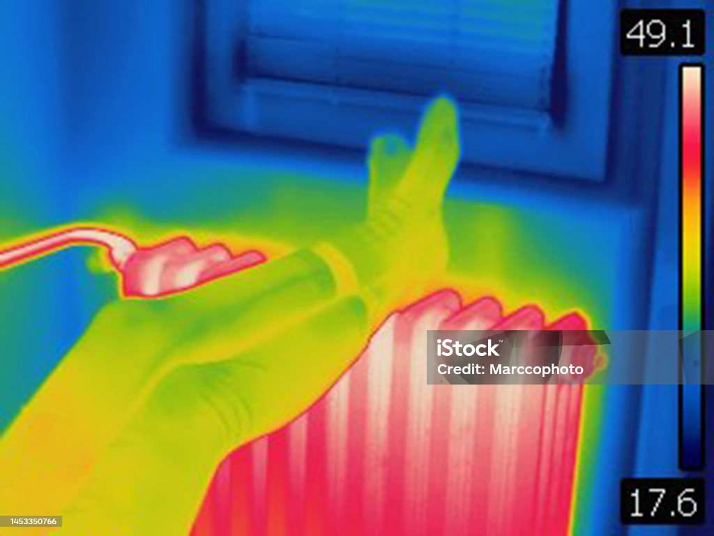 Thermal image of female legs on hot home heating radiator Image is taken with Flir T420 infra red camera. Each color represents different temperatures, as is shown on spectrum scale on right side of image. Adult Stock Photo