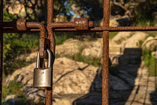 Close-up of a rusted iron door with a padlock. Security measures against theft in rural areas