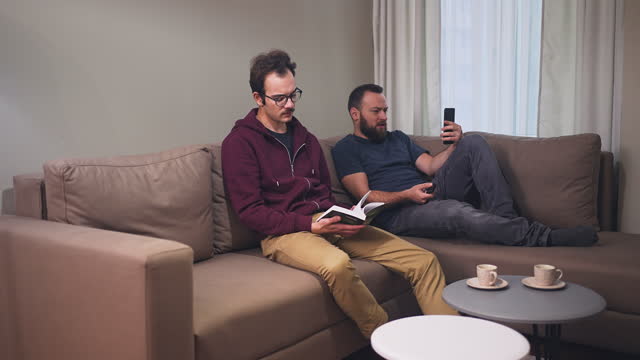 Two Males Using Manual Book To Set Up Television At Home