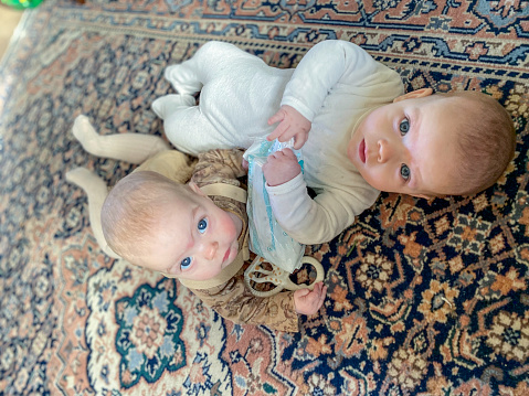 Cute baby brother and sister twin looking up laying on the floor