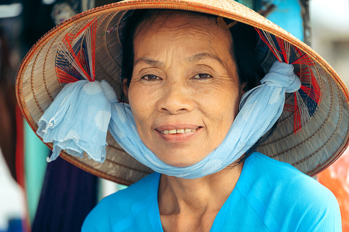 Portait of smiling vietnamese woman\nMarket vendor at Cai Rang floating market, Can Tho, Vietnam