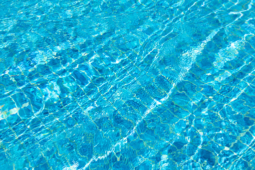 Turquoise pool water surface with ripples and waves on sunny day