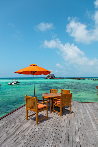 Tropical outdoor Bar Restaurant on wooden deck pier by the sea with turquoise lagoon