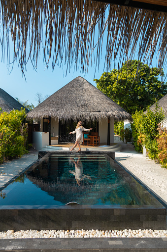 woman standing at Maldives hotel beach villa with swimming Pool on tropical Island Resort