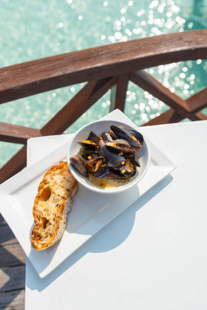 Mediterranean mussels in white wine sauce with garlic bread served at seaside seafood restaurant Mediterranean mussels in white wine sauce with garlic bread served at seaside seafood restaurant maldives fish market photos stock pictures, royalty-free photos & images