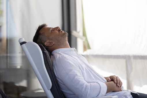 Man's on a porch armchair in summertime sleeping