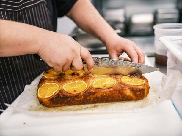 Close up of hands of male  chef working in restaurant kitchen. He is wearing usual kitchen attire with apron. Interior of industrial kitchen of a busy restaurant.