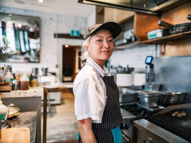 Young Korean female chef working in restaurant bar kitchen stock photo