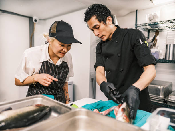 dois jovens chefs que trabalham na cozinha do restaurante - asian ethnicity chef fine dining creativity - fotografias e filmes do acervo