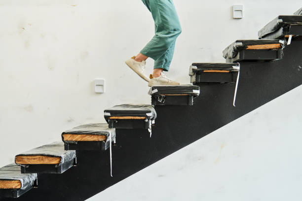 Unrecognizable woman walking up a flight of steps covered in protective plastic during an office renovation