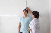 Female nutritionist and deportologist mesuring height of teenager patient  during medical consultation