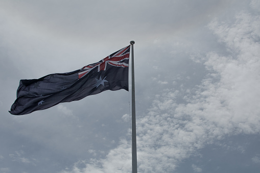 Australian flag from below with sky and clouds in background