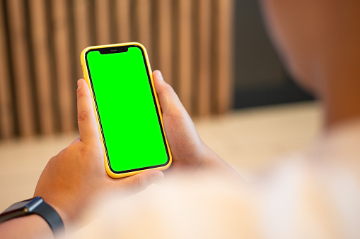 Teenage boy with iphone. Chroma key green screen on iphone for your design. Mockup template concept. Blank screen.